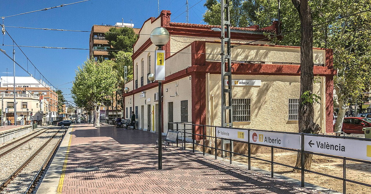 Andén de la estación de Alberic con el edificio de viajeros y el rótulo de la estación