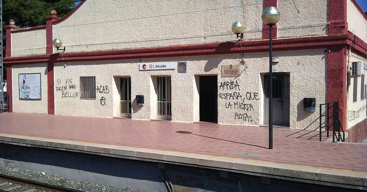 Edificio blanco y rojo de la estación de L’Alcúdia visto desde las vías
