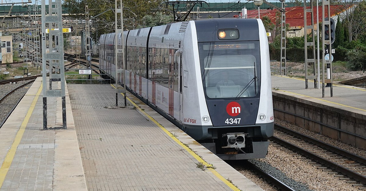 Tren blanco y rojo de Metrovalencia parado junto al andén de la estación de València Sud